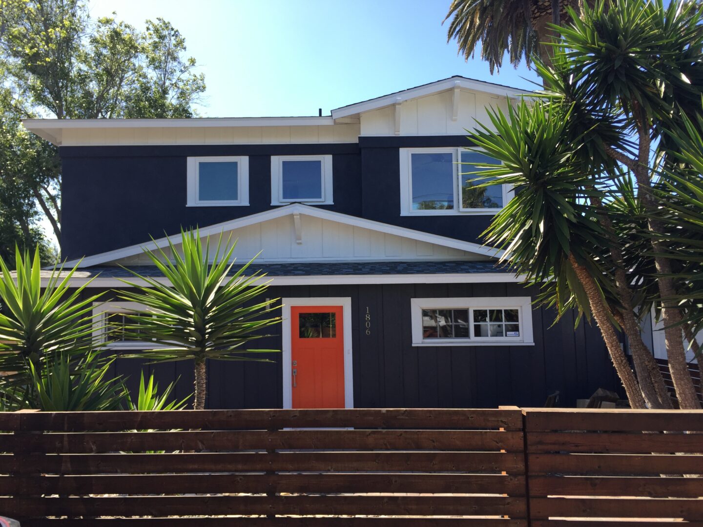 A black house with orange door and white trim.